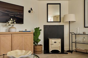 Una sala de estar moderna con chimenea, televisor montado en la pared, lámpara de pie y estantería.