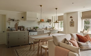A modern kitchen with a dining area, featuring a table, chairs, and a sofa with cushions. - The Georgian House (Ludlow)
