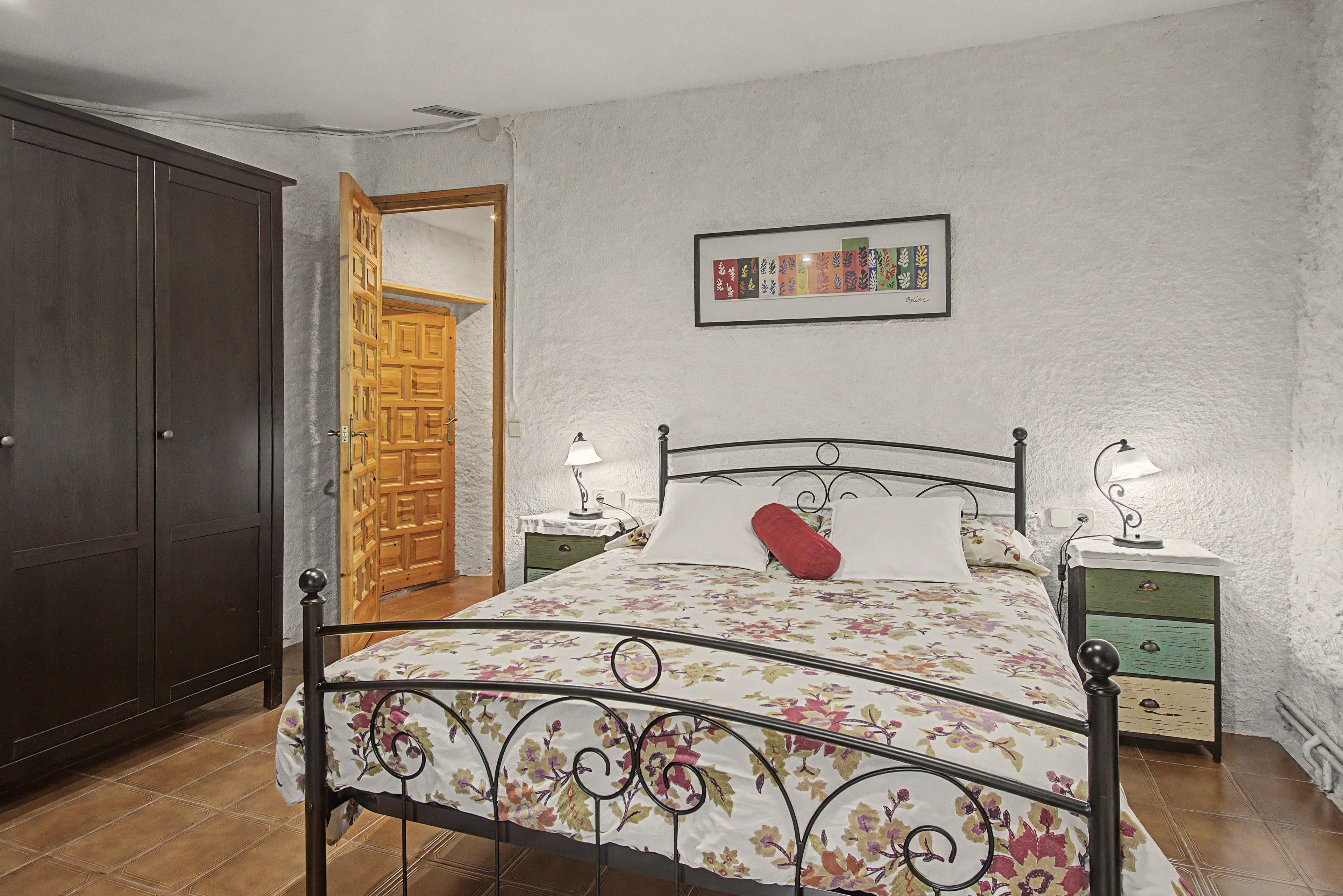 Un dormitorio con cama, mesitas de noche, armario y puerta.