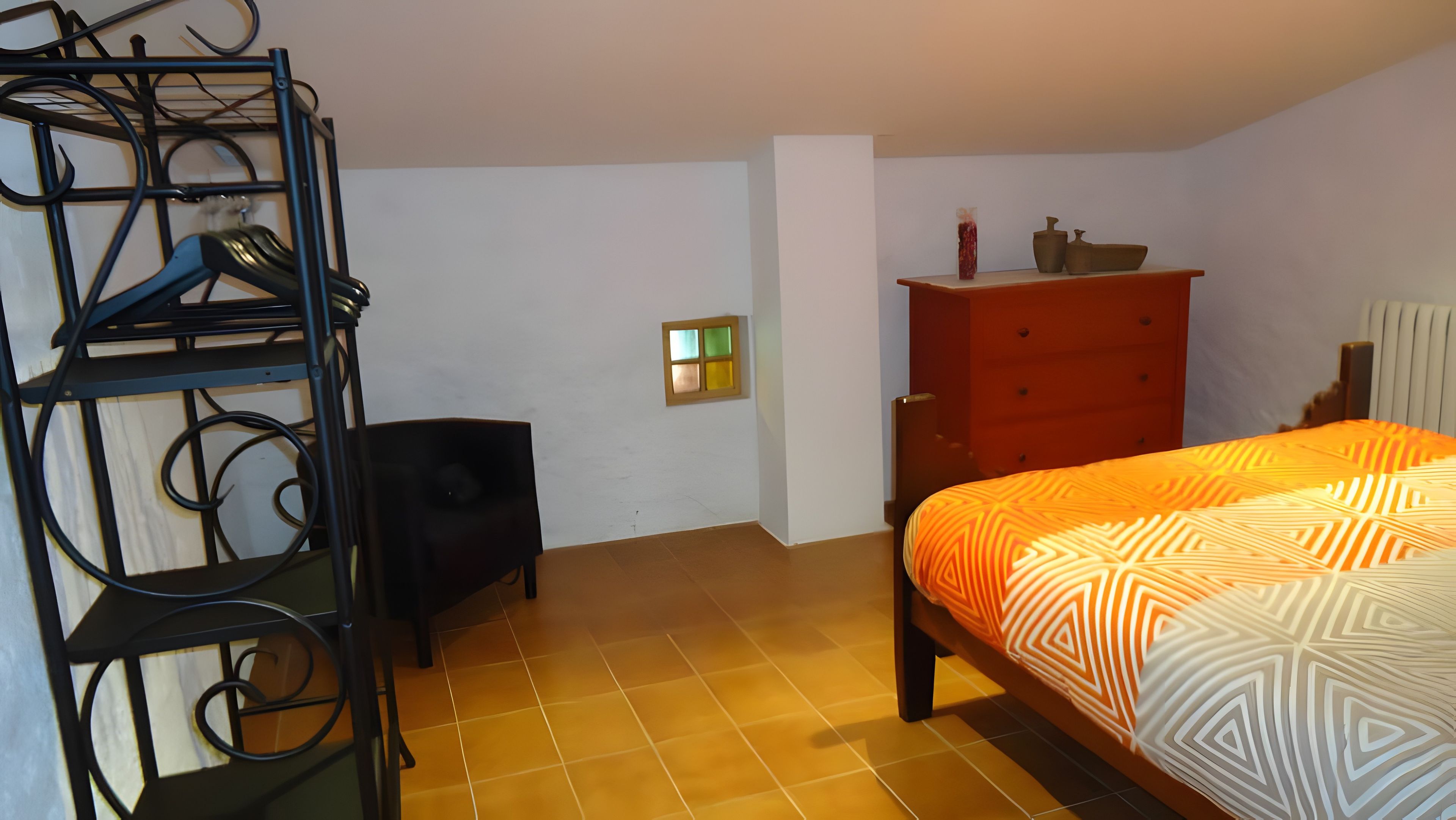 Quarto com cama, cómoda e um alto-falante.