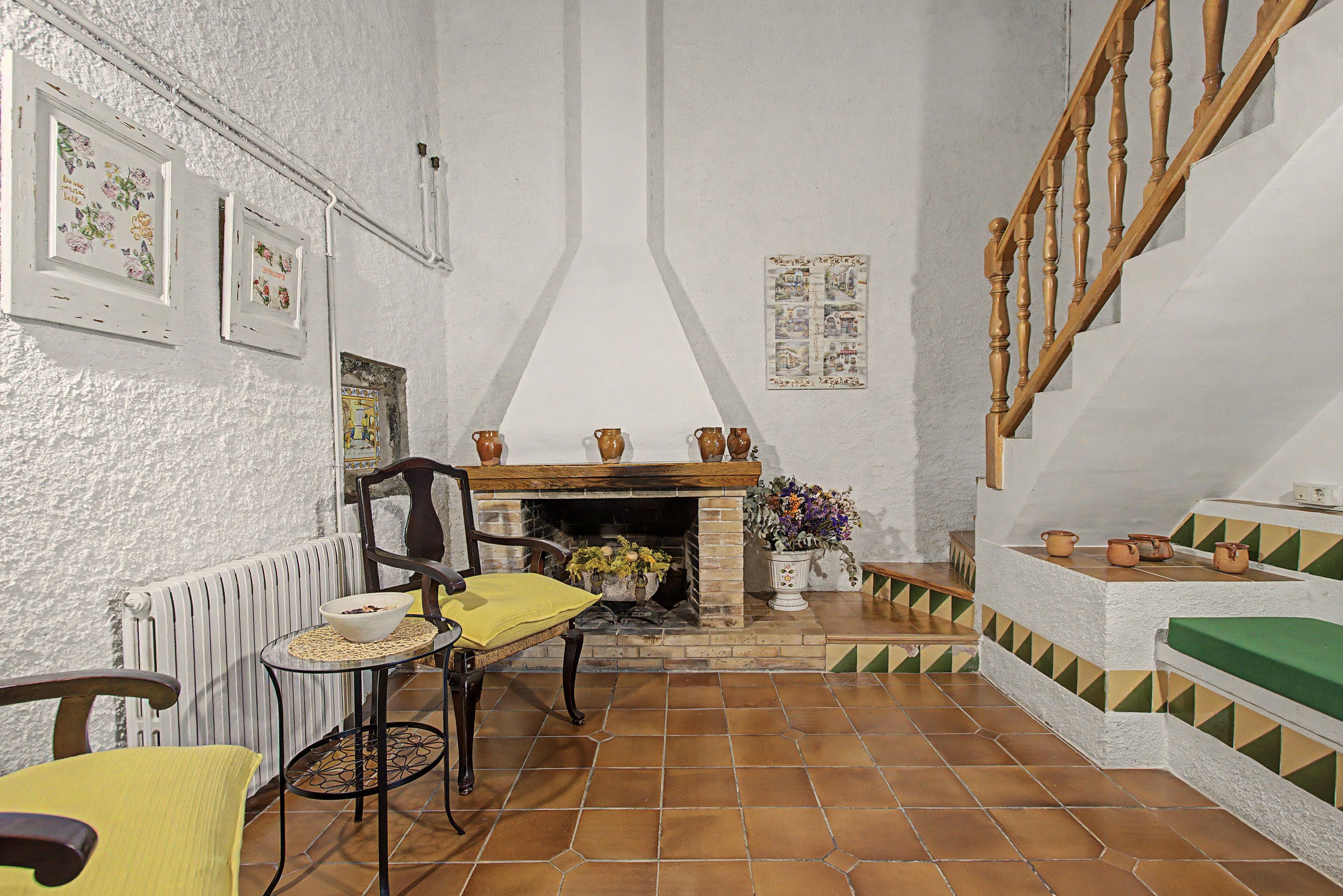Una sala de estar acogedora con chimenea, una escalera de madera y un comedor con mesa y sillas.