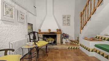 Una sala de estar acogedora con chimenea, una escalera de madera y un comedor con mesa y sillas.