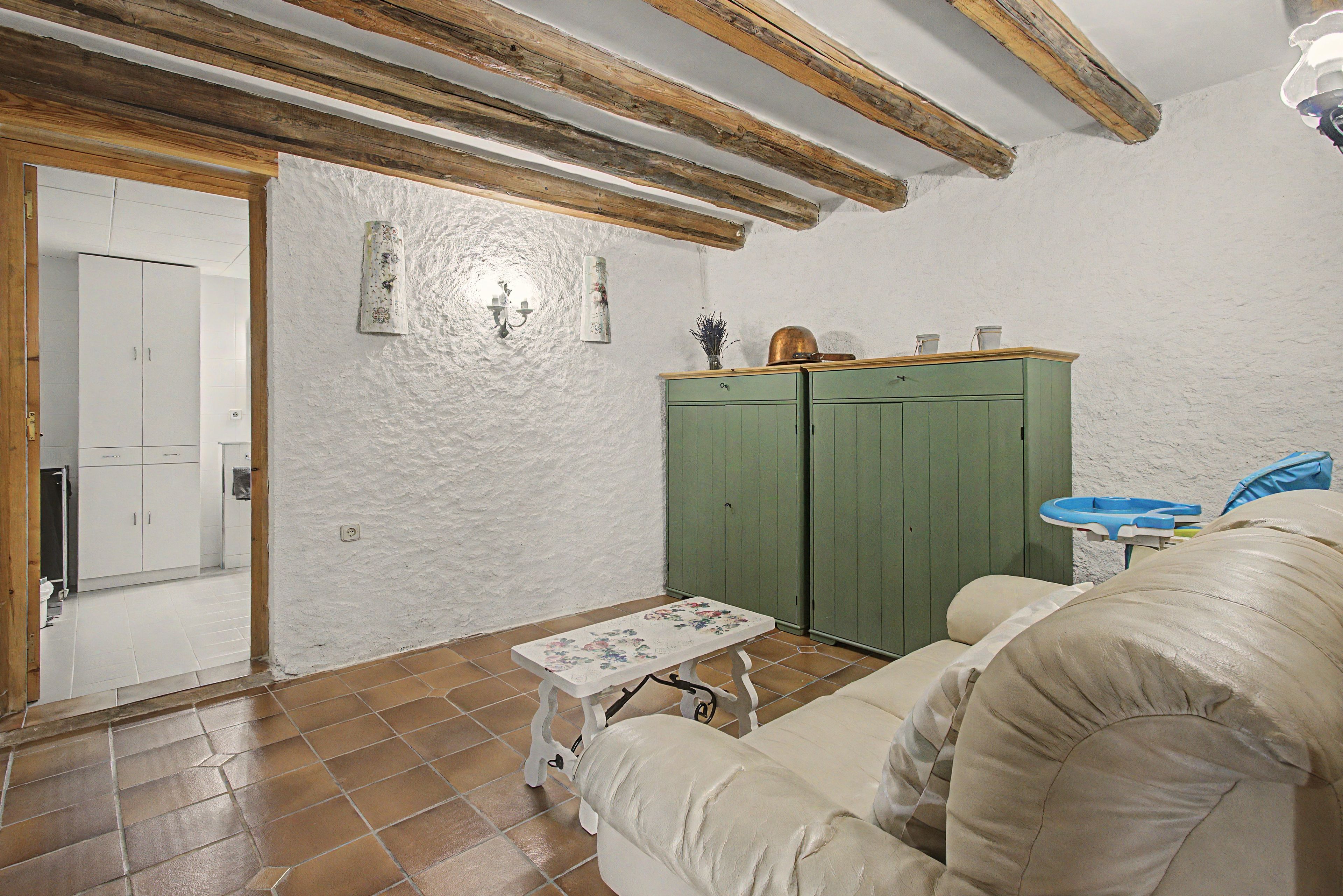 A room with a green wardrobe, a white sofa, a small table, and a tiled floor.