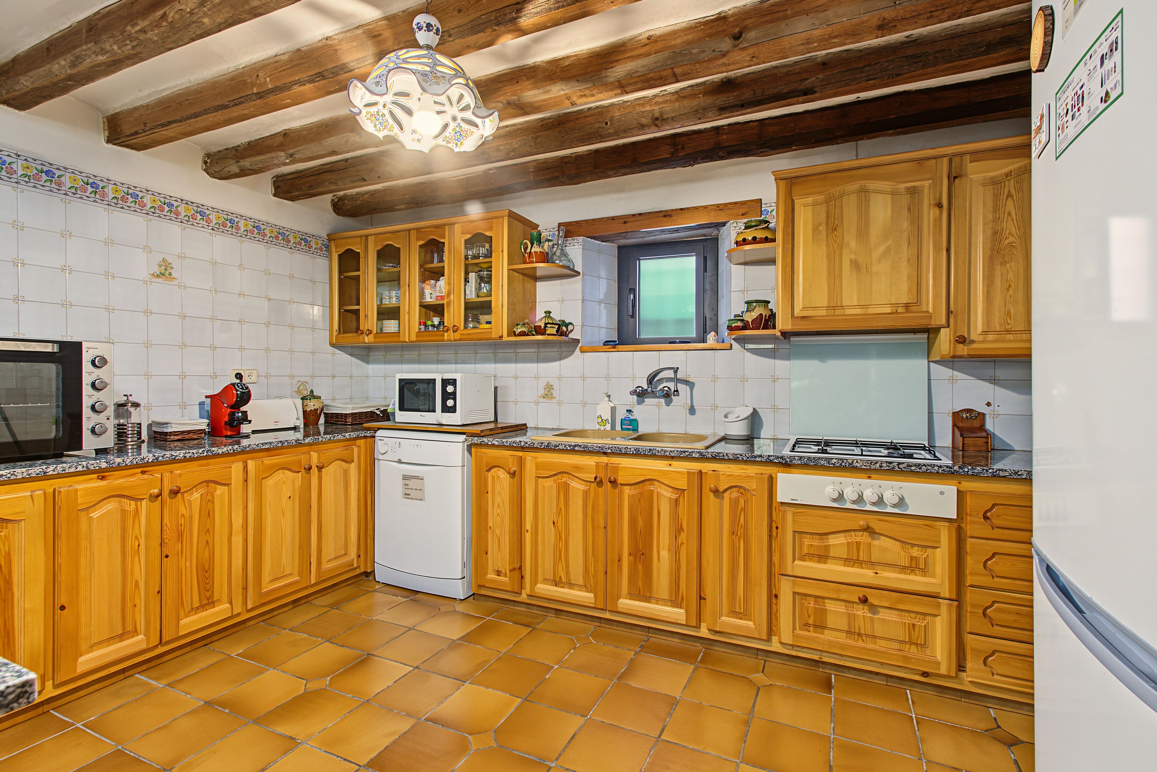 Una cocina con gabinetes de madera, estufa, microondas y pileta.