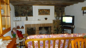 A living room with a fireplace, television, and various decorative items. - Holiday Home 'Masia De Can Creus 1890' (Girona)