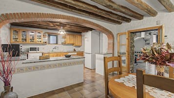 Une cuisine dotée d’un îlot central, de meubles en bois et d’une arche en pierre.