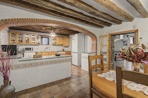 Een keuken met een centraal eiland, houten kasten en een stenen boog.