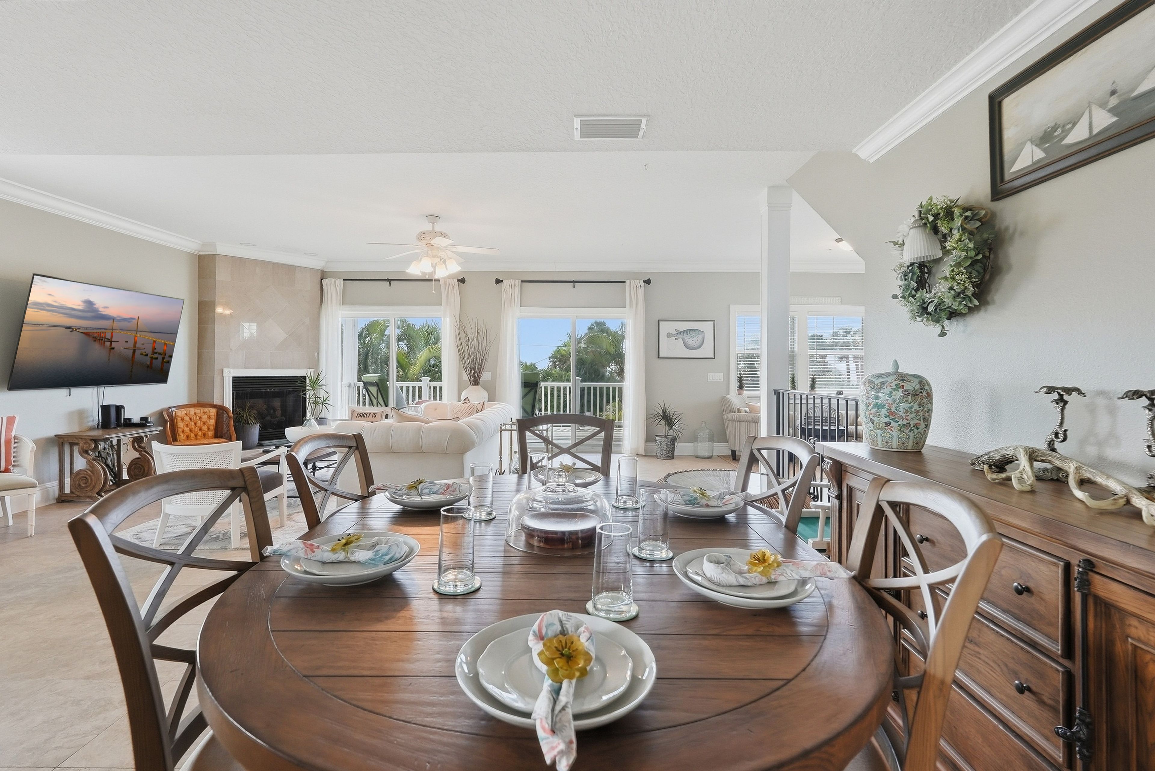 Un coin repas avec une table ronde dressée pour quatre personnes, entourée de chaises, et offrant une vue sur l’extérieur grâce à de grandes fenêtres.