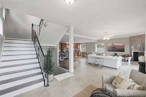 A spacious living area with a staircase, a kitchen, and a seating area with a fireplace. - Redington Beach Getaway  A Short Walk to the Gulf (Redington Beach)