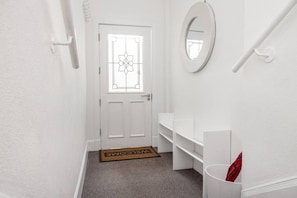 A hallway with a white door, a welcome mat, a mirror, and a white wall. - 2 Bed Main Door Apt on Leith Walk, Near Tram (Edinburgh)