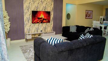 Una sala de estar con un juego de sofá, un televisor de pantalla plana y una chimenea.