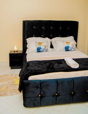 A bed with a black upholstered headboard, white bedding, and decorative pillows with nature-themed designs.