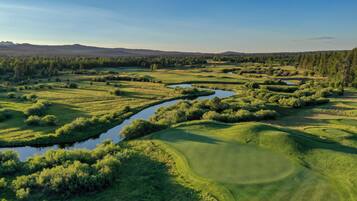 Un parcours de golf agrémenté d’obstacles d’eau, d’une végétation luxuriante et offrant une vue sur des montagnes lointaines.