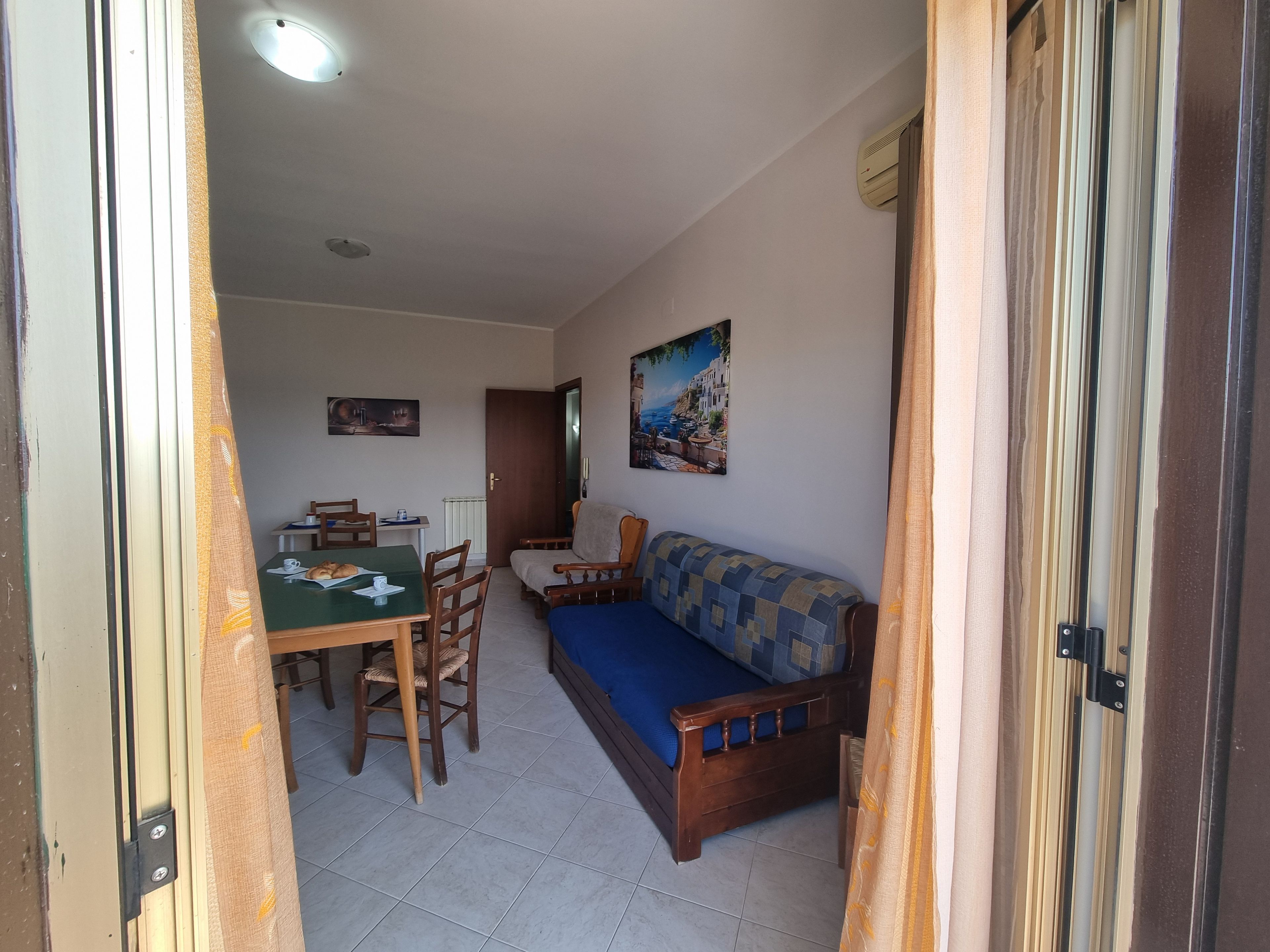 Une pièce comprenant une table à manger, des chaises, un canapé et un tableau accroché au mur.