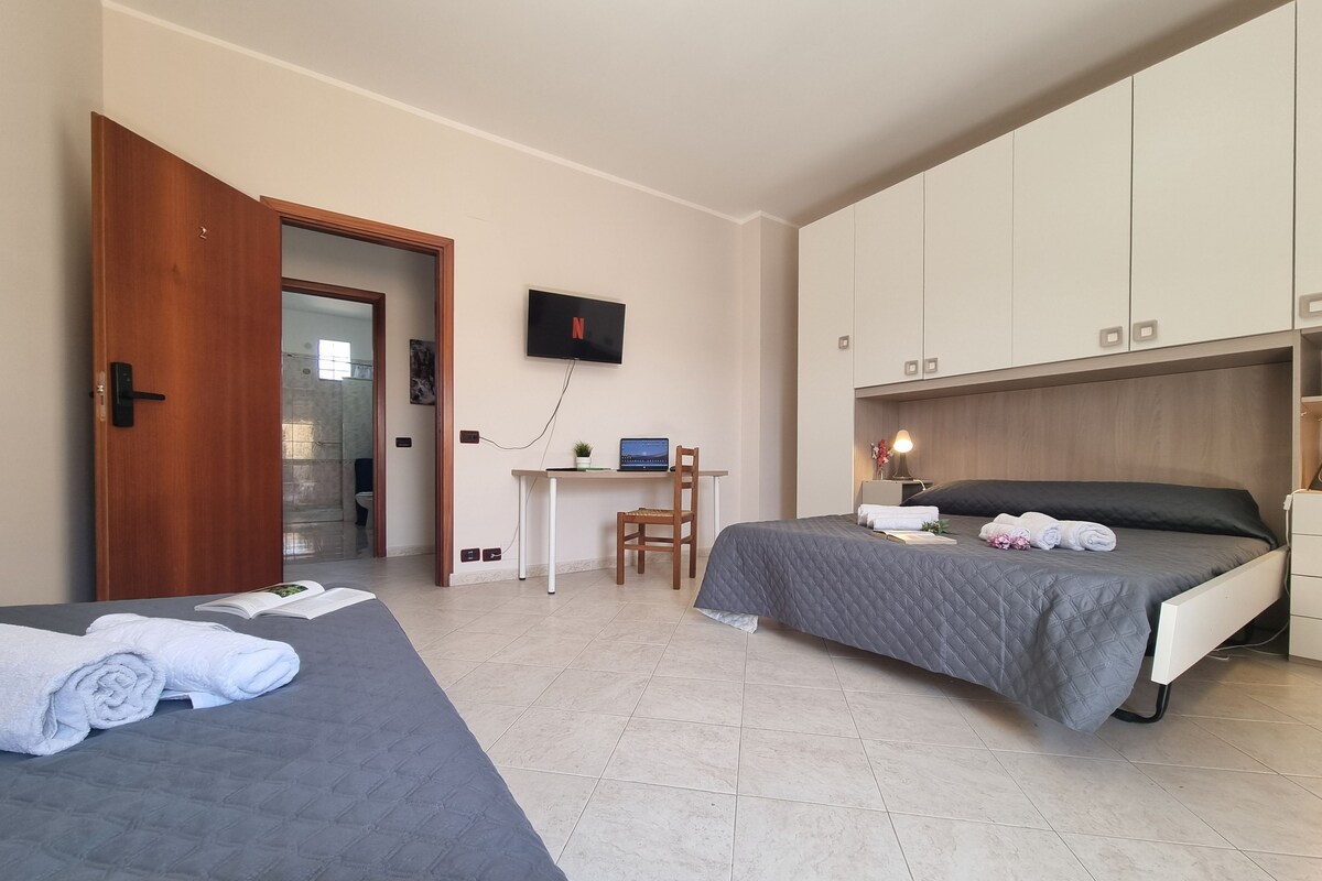 Ein Hotelzimmer mit zwei Betten, einem Schreibtisch mit Computer, einem Fernseher und einem Kleiderschrank.