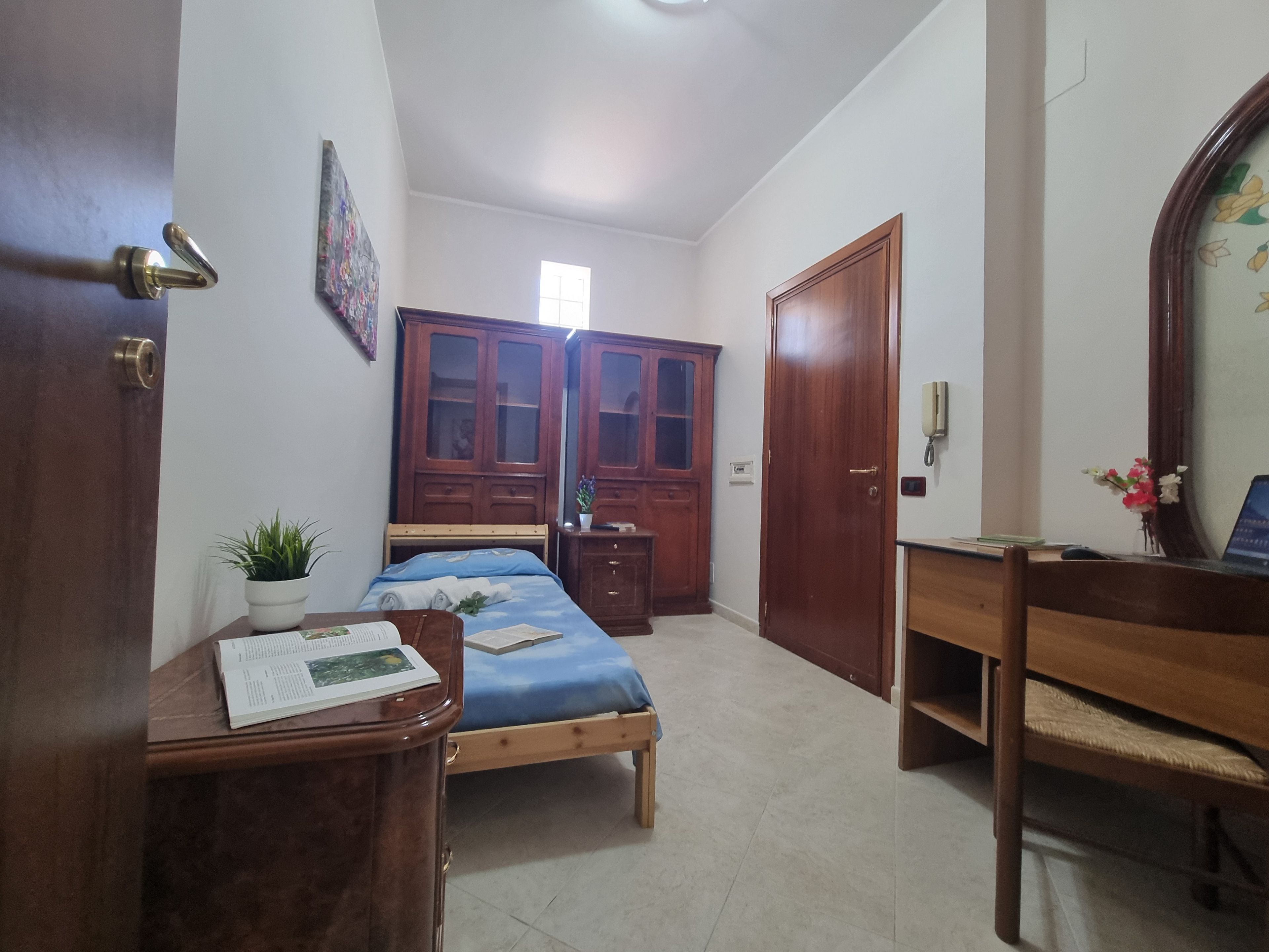 Une chambre à coucher avec un lit, un bureau, une armoire et un miroir.