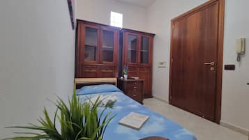Un dormitorio con una cama, un armario de madera, una mesita de noche y una planta en maceta.