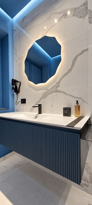 A modern bathroom with a large mirror, two sinks, and a blue accent wall. - Lungofiume Suite | Entire apartment with terrace, 3 bedrooms and 2 bathrooms (Avellino)