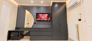A modern interior with a flat-screen TV mounted on a dark wall, a built-in bench, and a small cabinet labeled 'CREATE'. - Lungofiume Suite | Entire apartment with terrace, 3 bedrooms and 2 bathrooms (Avellino)