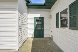A narrow, covered entryway with a green door, white siding, and a stone-paved ground. - Lake and Trailside Ranch house in rural Augusta (Augusta)