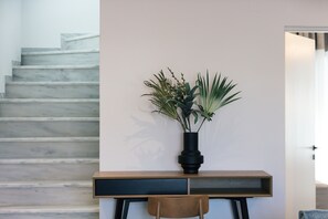 A staircase with a modern design, a wooden desk with a black vase containing green plants, and a wooden chair. - Queen Bee Villa in Prinos (Rethymno)