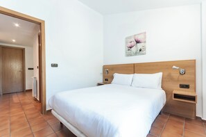Ein Schlafzimmer mit hölzernem Kopfteil, einem Bett mit weißen Leinen, einem Nachttisch mit Lampe und einem Gemälde an der Wand.