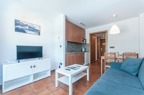 Ein modernes Wohnzimmer mit einem Flachbildfernseher, einem weißen Couchtisch und einem blauen Sofa.
