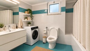 A modern bathroom with a washing machine, toilet, and a window above the sink. - Luesh ΙΙ · Large 2BR Apt | Walk to Beach and Center (Agios Nikolaos)