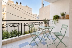 Ein Balkon mit Tisch und Stühlen, einem Blumentopf und Blick auf die Stadtlandschaft.