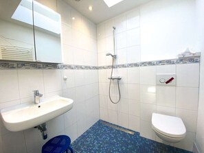 Ein Badezimmer mit Waschbecken, Toilette, Dusche und einem gemusterten Boden.