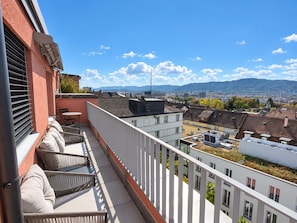 A balcony with outdoor seating, a view of the cityscape, and a clear sky. - Stylish 1-Bedroom Apartment with a View of Zurich - Tilia 52 (Zürich)