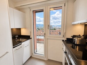 A compact kitchen with a sliding glass door leading to an outdoor balcony. - Stylish 1-Bedroom Apartment with a View of Zurich - Tilia 52 (Zürich)