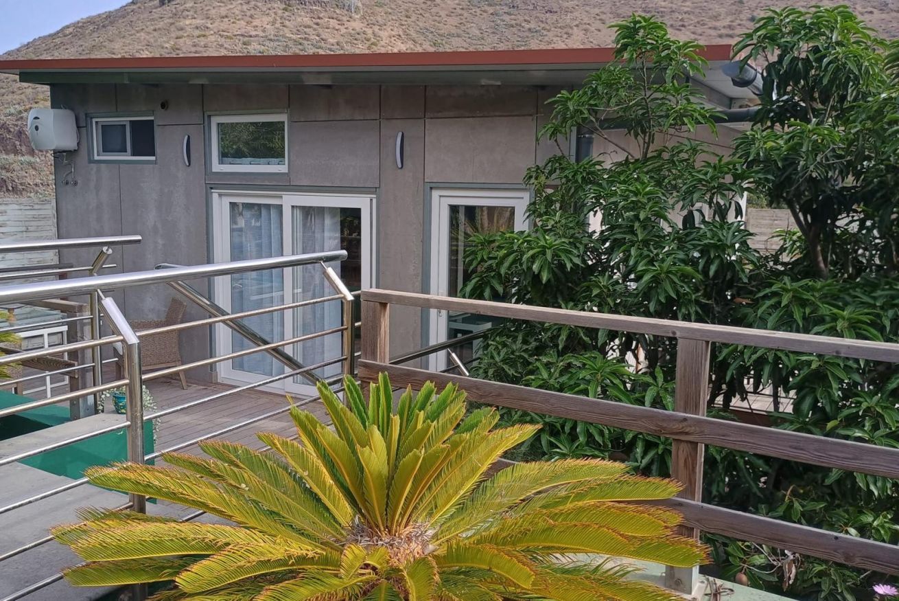 A building with a staircase leading to a deck area, surrounded by greenery.