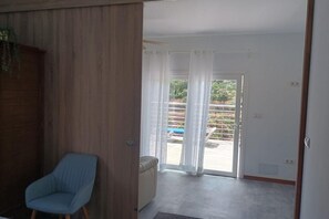 Habitació amb porta corredissa de vidre que dona a una zona exterior amb piscina i mobiliari.