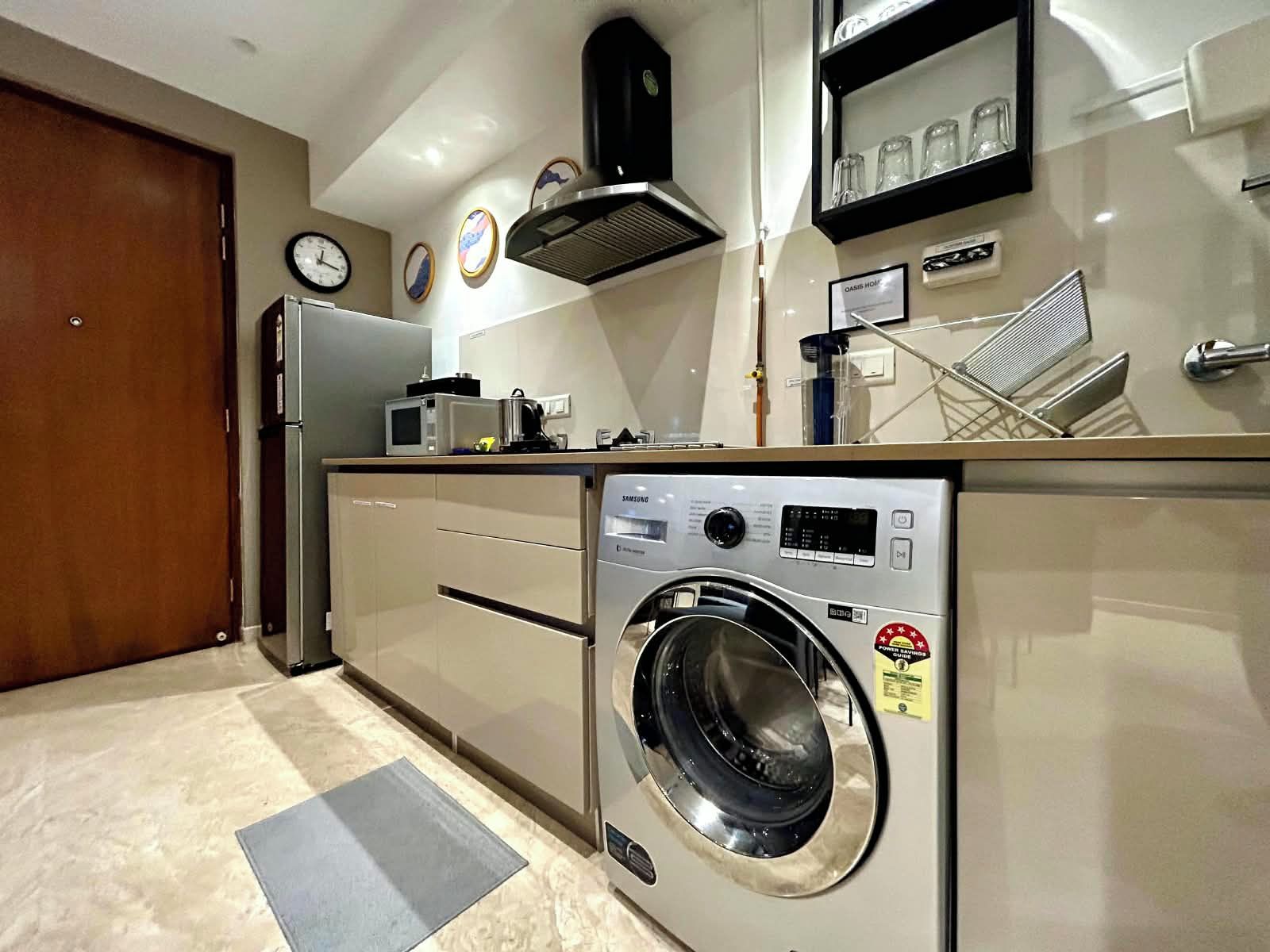 A compact kitchen with a built-in washer and dryer, a microwave, and a refrigerator.