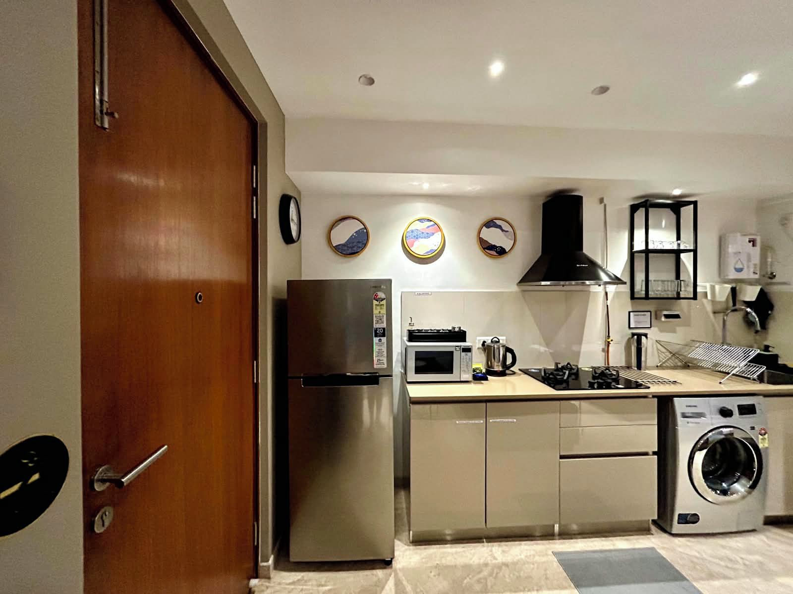 A compact kitchen with a refrigerator, microwave, stove, sink, and washing machine.