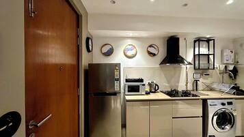 A compact kitchen with a refrigerator, microwave, stove, sink, and washing machine.
