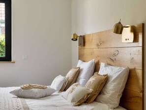 A bedroom with a wooden headboard, white bedding, and two wall-mounted lamps. - Holiday Home in Renesse With Wi-fi (Renesse)