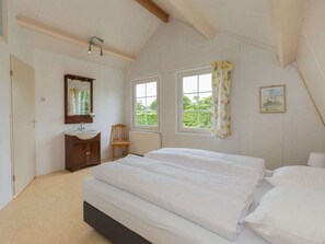 A bedroom with two beds, a window, a mirror, and a small chair. - Holiday Home in Renesse With Swimming Pool (Renesse)