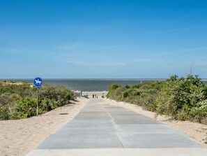 A paved pathway leading to a beach with a clear blue sky. - Holiday Home in Renesse With Swimming Pool (Renesse)