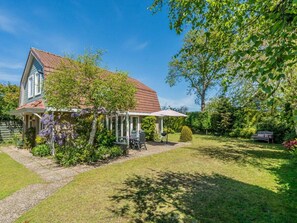 A house with a covered porch, a garden with a lawn, and a bench. - Holiday Home in Renesse With Swimming Pool (Renesse)
