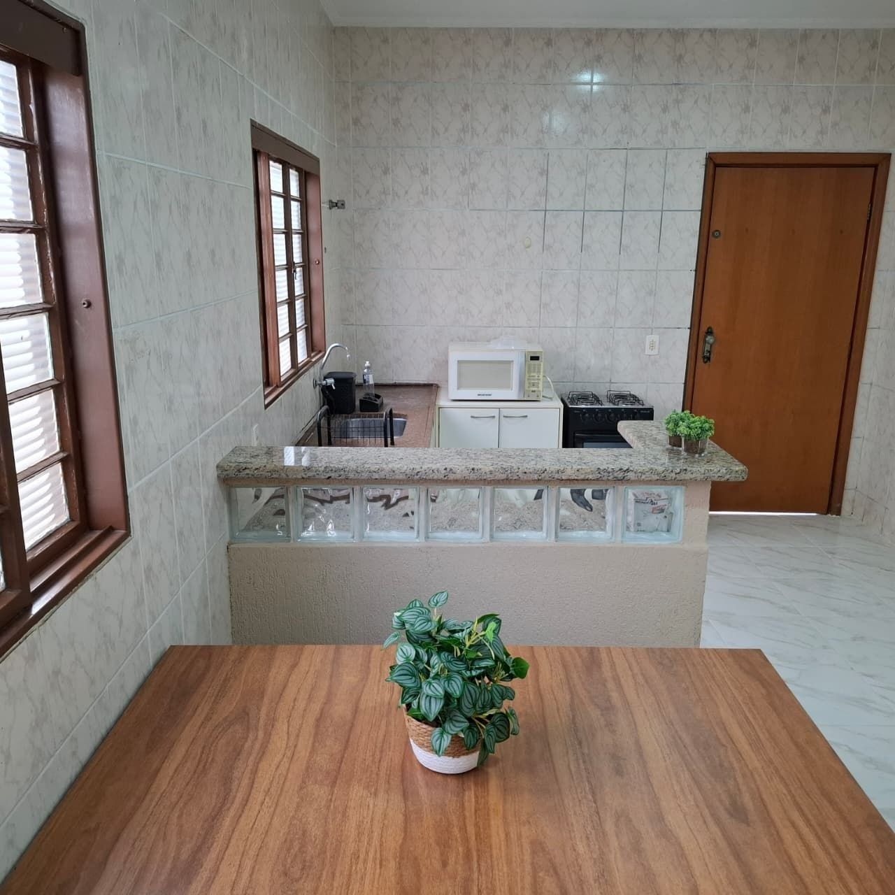 A kitchen with a marble countertop, a microwave, a stove, and a sink.