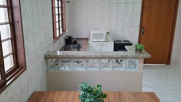 A kitchen with a marble countertop, a microwave, a stove, and a sink.