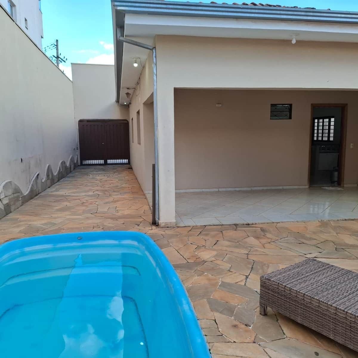 A courtyard with a swimming pool, a covered area, and a tiled patio.