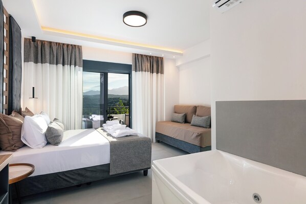 Een moderne hotelkamer met een groot bed, een bank, een badkuip en uitzicht op de omgeving.