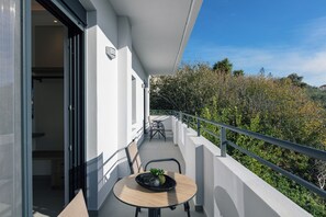 A balcony with a table and chairs, overlooking a forested hillside. - Queen Bee Villa - Four Bedroom Villa, Sleeps 10 (Prinos)
