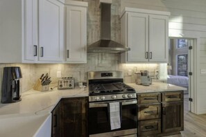 A kitchen with white cabinets, a stainless steel stove, a toaster, and a coffee maker. - LUXE Chalet Hot tub, Amazing view, 10 min downtown (Blue Ridge)