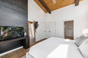 A bedroom with a large bed, a mounted TV, a fireplace, and a door leading to another room. - LUXE Chalet Hot tub, Amazing view, 10 min downtown (Blue Ridge)