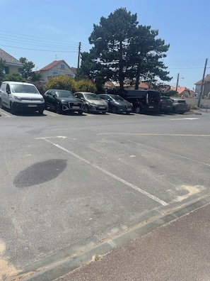 A parking lot with several cars, a stop sign, and a large tree. - Villa Mont Plaisir, just a stone's throw from the beach. Pets allowed. (Langrune-sur-Mer)