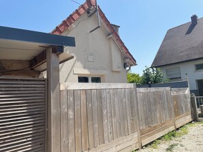 A house with a wooden fence, a garage door, and a red roof. - Villa Mont Plaisir, just a stone's throw from the beach. Pets allowed. (Langrune-sur-Mer)